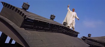 Movie still from “Lawrence of Arabia” (1962), directed by David Lean – A man standing on top of a building holding a cell phone; Wide shot, Low angle