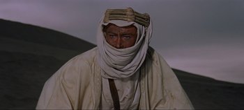 Movie still from “Lawrence of Arabia” (1962), directed by David Lean – A man wearing a white turban and a white robe; Medium shot, Over the shoulder angle