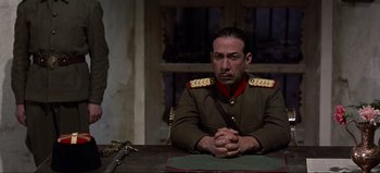 Movie still from “Lawrence of Arabia” (1962), directed by David Lean – A man in a military uniform sitting at a table; Medium shot, Low angle