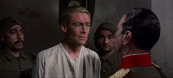 Movie still from “Lawrence of Arabia” (1962), directed by David Lean – A man in a white shirt is looking at another man in a uniform; Close Up shot, Over the shoulder angle