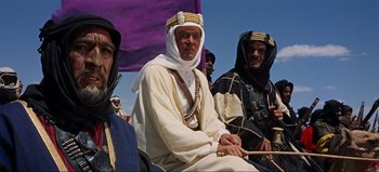 Movie still from “Lawrence of Arabia” (1962), directed by David Lean – A group of men sitting next to each other on top of a hill; Medium shot, Low angle