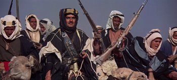 Movie still from “Lawrence of Arabia” (1962), directed by David Lean – A group of men standing next to each other holding guns; Medium shot, Low angle
