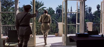 Movie still from “Lawrence of Arabia” (1962), directed by David Lean – A man walking on a balcony looking out at a city; Wide shot, Over the shoulder angle