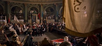 Movie still from “Lawrence of Arabia” (1962), directed by David Lean – A group of people sitting on a stage in front of an audience; Extreme Wide shot, High angle
