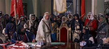 Movie still from “Lawrence of Arabia” (1962), directed by David Lean – A group of men standing in front of a table; Wide shot, Over the shoulder angle