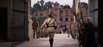 Movie still from “Lawrence of Arabia” (1962), directed by David Lean – A group of men in uniform walking down a street; Wide shot, Low angle