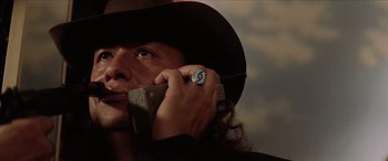 Movie still from “Léon: The Professional” (1994), directed by Luc Besson – A man in a cowboy hat talking on a cell phone; Close Up shot, Low angle