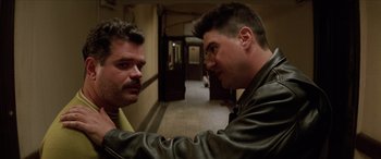 Movie still from “Léon: The Professional” (1994), directed by Luc Besson – Two men in leather jackets are facing each other in a hallway; Close Up shot, Over the shoulder angle