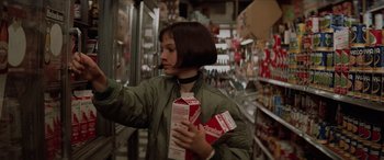 Movie still from “Léon: The Professional” (1994), directed by Luc Besson – A woman in a grocery store holding milk boxes; Medium shot, Low angle
