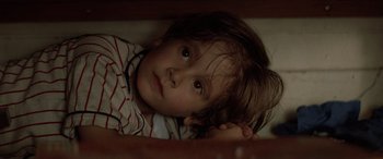 Movie still from “Léon: The Professional” (1994), directed by Luc Besson – A young child laying in a bed looking up at the camera; Close Up shot, High angle