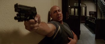 Movie still from “Léon: The Professional” (1994), directed by Luc Besson – A bald man holding a gun in a room; Medium shot, High angle