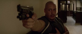 Movie still from “Léon: The Professional” (1994), directed by Luc Besson – A bald man holding a gun in a room; Medium shot, High angle