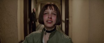 Movie still from “Léon: The Professional” (1994), directed by Luc Besson – A young woman with short brown hair wearing a green jacket; Close Up shot, Over the shoulder angle
