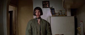 Movie still from “Léon: The Professional” (1994), directed by Luc Besson – A person standing next to a refrigerator in a room; Medium shot, Low angle