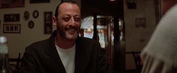 Movie still from “Léon: The Professional” (1994), directed by Luc Besson – A man smiling for the camera while wearing a jacket; Close Up shot, Low angle