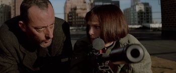 Movie still from “Léon: The Professional” (1994), directed by Luc Besson – A woman with short hair is holding a camera; Close Up shot, Over the shoulder angle