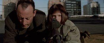 Movie still from “Léon: The Professional” (1994), directed by Luc Besson – A young girl is holding a microphone in front of a man; Close Up shot, Over the shoulder angle