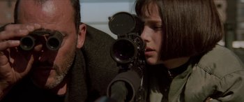 Movie still from “Léon: The Professional” (1994), directed by Luc Besson – A man and a woman looking through a camera; Close Up shot, Over the shoulder angle