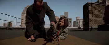 Movie still from “Léon: The Professional” (1994), directed by Luc Besson – A man and a girl looking at a rifle; Medium shot, Low angle