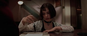Movie still from “Léon: The Professional” (1994), directed by Luc Besson – A young woman is writing on a piece of paper; Close Up shot, High angle