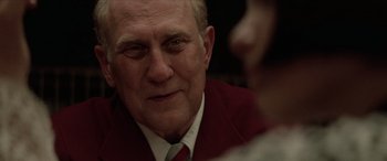 Movie still from “Léon: The Professional” (1994), directed by Luc Besson – An older man wearing a red jacket and a white tie; Close Up shot, Over the shoulder angle