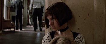 Movie still from “Léon: The Professional” (1994), directed by Luc Besson – A young woman with short brown hair wearing a necklace; Close Up shot, Over the shoulder angle