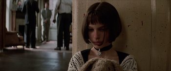 Movie still from “Léon: The Professional” (1994), directed by Luc Besson – A woman with a teddy bear sitting in a room; Close Up shot, Low angle