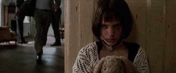 Movie still from “Léon: The Professional” (1994), directed by Luc Besson – A young woman holding a teddy bear while wearing a necklace; Close Up shot, Low angle