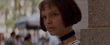Movie still from “Léon: The Professional” (1994), directed by Luc Besson – A woman with short brown hair wearing a black choker; Close Up shot, Low angle