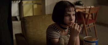 Movie still from “Léon: The Professional” (1994), directed by Luc Besson – A woman sitting on a couch with her hand under her chin; Close Up shot, Low angle