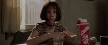 Movie still from “Léon: The Professional” (1994), directed by Luc Besson – A woman sitting on a couch holding a glass of water; Close Up shot, High angle