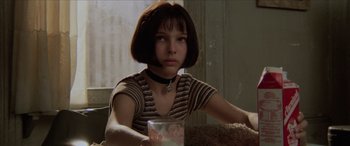 Movie still from “Léon: The Professional” (1994), directed by Luc Besson – A young woman sitting at a table with a cup of coffee; Close Up shot, Low angle
