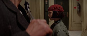 Movie still from “Léon: The Professional” (1994), directed by Luc Besson – A young boy wearing a red hat is holding a guitar; Close Up shot, Over the shoulder angle