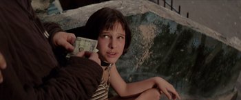 Movie still from “Léon: The Professional” (1994), directed by Luc Besson – A young girl holding a dollar bill in her hand; Close Up shot, Over the shoulder angle