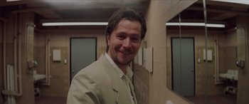 Movie still from “Léon: The Professional” (1994), directed by Luc Besson – A man in a beige suit smiling for the camera; Close Up shot, Low angle