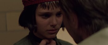 Movie still from “Léon: The Professional” (1994), directed by Luc Besson – A young person looking into a mirror with a red hat on; Close Up shot, Over the shoulder angle