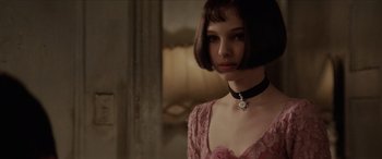 Movie still from “Léon: The Professional” (1994), directed by Luc Besson – A woman in a pink dress with a black choker; Close Up shot, Over the shoulder angle