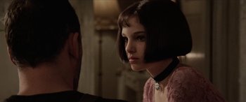 Movie still from “Léon: The Professional” (1994), directed by Luc Besson – A woman with short black hair wearing a pink dress; Close Up shot, Over the shoulder angle