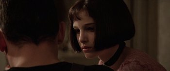 Movie still from “Léon: The Professional” (1994), directed by Luc Besson – A woman with short black hair wearing a black choker; Close Up shot, Over the shoulder angle