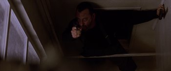 Movie still from “Léon: The Professional” (1994), directed by Luc Besson – A man holding a gun in a dark room; Close Up shot, Overhead angle