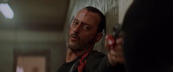 Movie still from “Léon: The Professional” (1994), directed by Luc Besson – A person holding a gun in a room; Close Up shot, Low angle