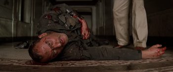 Movie still from “Léon: The Professional” (1994), directed by Luc Besson – A man laying on the ground covered in blood; Medium shot, Overhead angle
