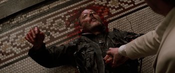 Movie still from “Léon: The Professional” (1994), directed by Luc Besson – A man is laying on the ground with blood on his face; Close Up shot, Overhead angle