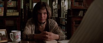 Movie still from “Léon: The Professional” (1994), directed by Luc Besson – A woman sitting at a table in front of a book; Close Up shot, Low angle