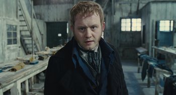 Movie still from “Les Misérables” (2012), directed by Tom Hooper – A man in a black jacket and a tie; Close Up shot, High angle