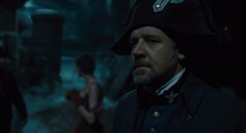 Movie still from “Les Misérables” (2012), directed by Tom Hooper – A man wearing a pirate hat in a dark setting; Close Up shot, Over the shoulder angle