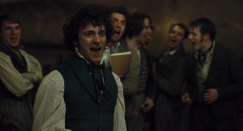 Movie still from “Les Misérables” (2012), directed by Tom Hooper – A group of people singing in a room; Medium shot, Low angle