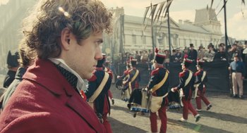 Movie still from “Les Misérables” (2012), directed by Tom Hooper – A group of men in red and black uniforms marching down a street; Close Up shot, Over the shoulder angle