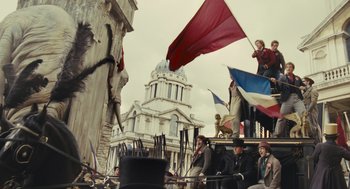 Movie still from “Les Misérables” (2012), directed by Tom Hooper – A group of people sitting on top of a building; Wide shot, Low angle