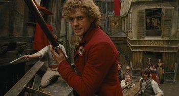 Movie still from “Les Misérables” (2012), directed by Tom Hooper – A man in a red jacket holding a sword; Medium shot, Over the shoulder angle